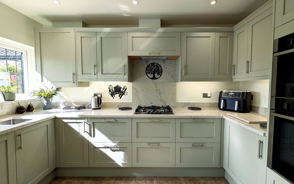 Taupe-green shaker U-shaped kitchen with quartz worktops and stainless steel handles
