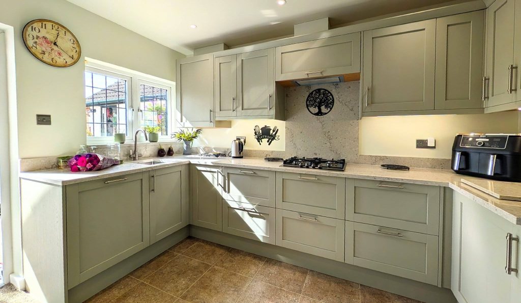 Taupe-green Shaker kitchen with Quartz worktops, stainless steel handles and integrated appliances